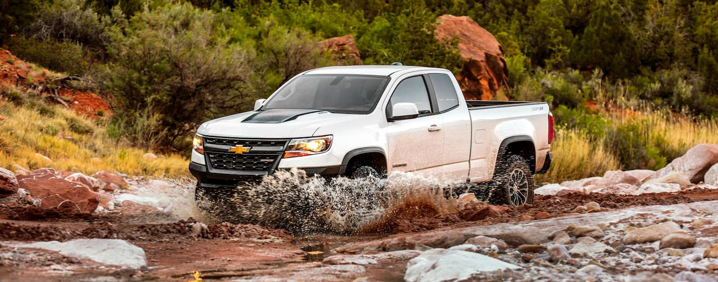 A white 2021 Chevy Colorado ZR2 is shown driving through a river after leaving a Chevrolet Colorado dealer.