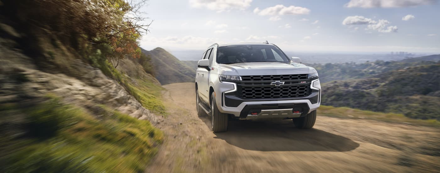 A white 2022 Chevy Tahoe Z71 is shown front the front driving on a dirt path.