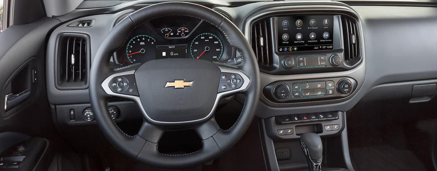 The black interior of a 2022 Chevy Colorado shows the steering wheel and infotainment screen.