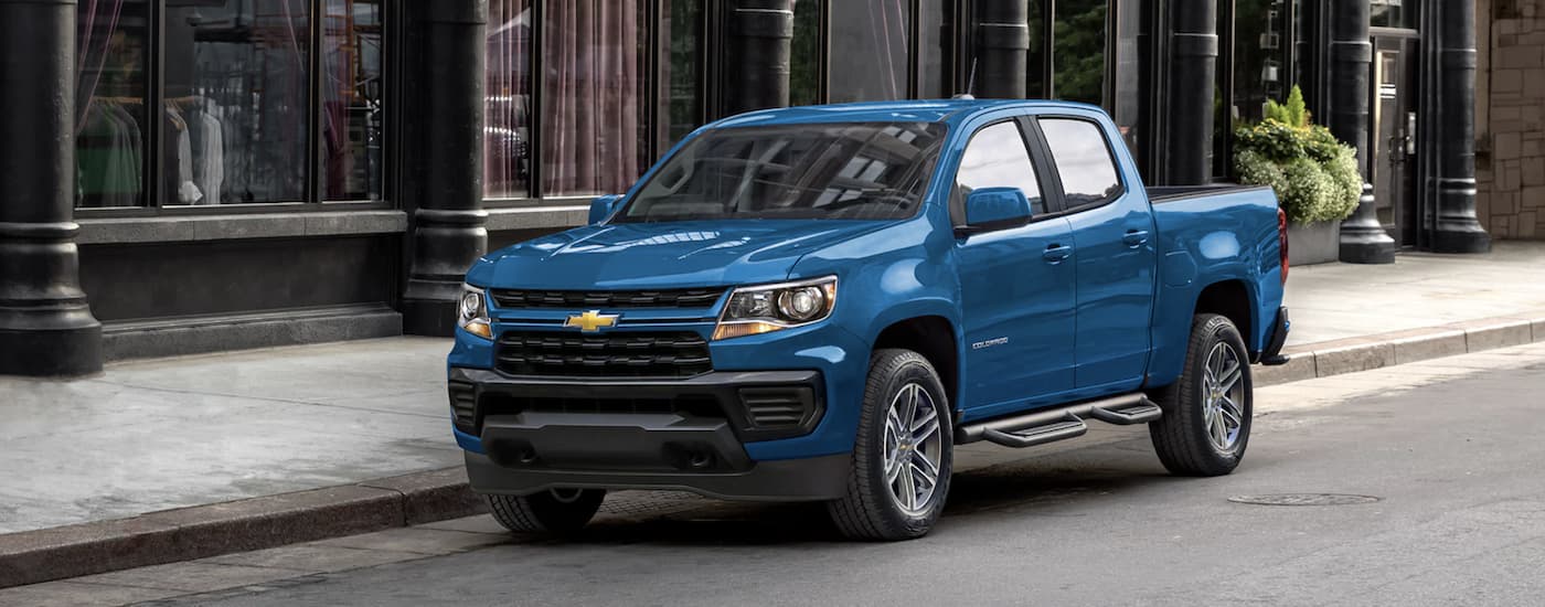 A blue 2022 Chevy Colorado is shown from the front parked on a city street.