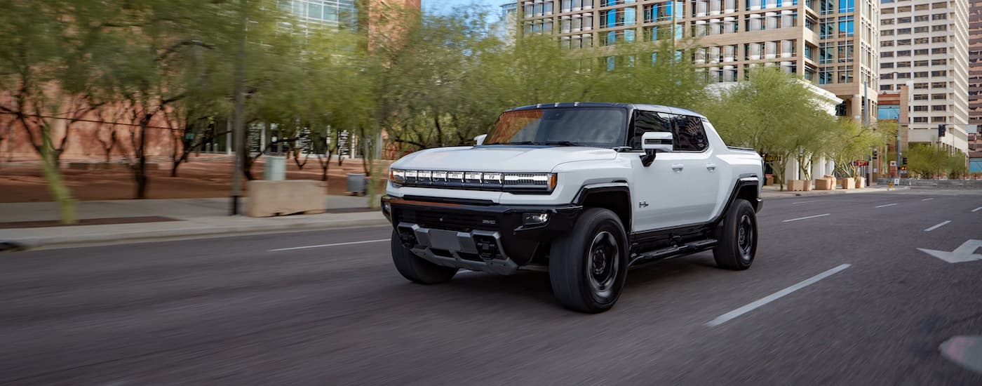 A white 2021 GMC Hummer EV is shown driving on a city street after leaving a Chevy dealer near you.