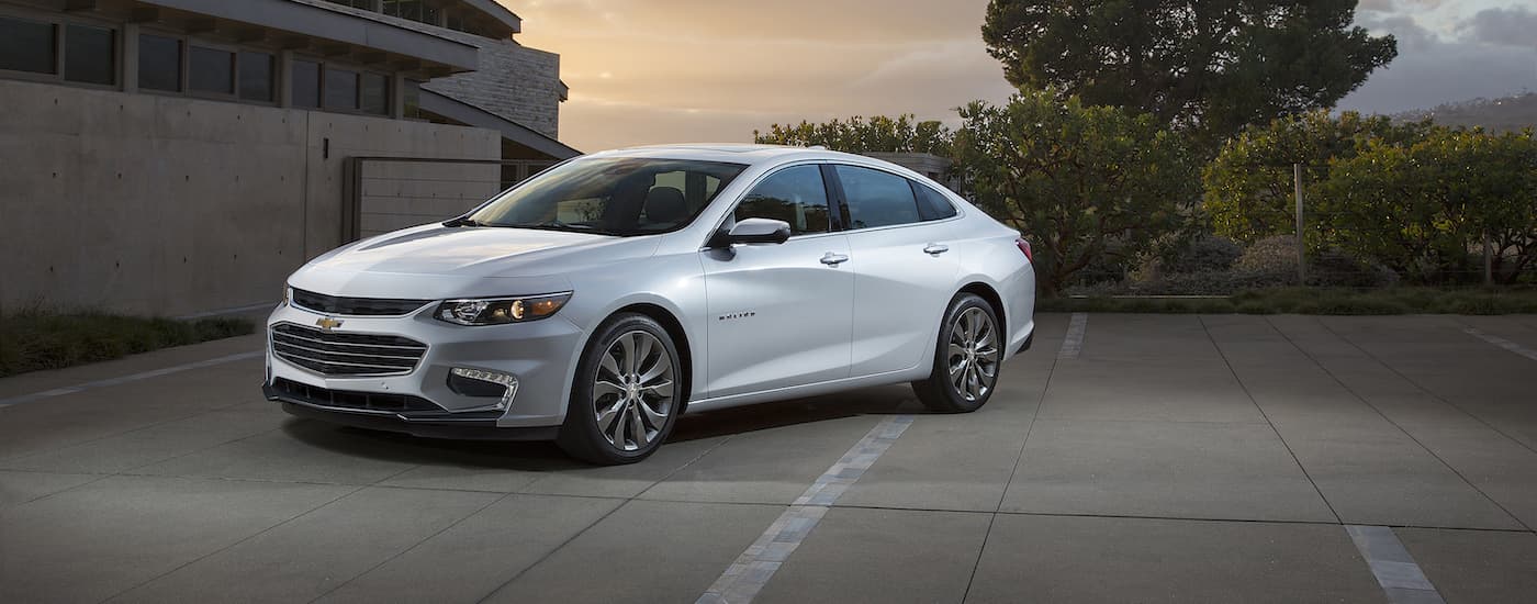A white 2016 Chevy Malibu is shown parked on concrete.