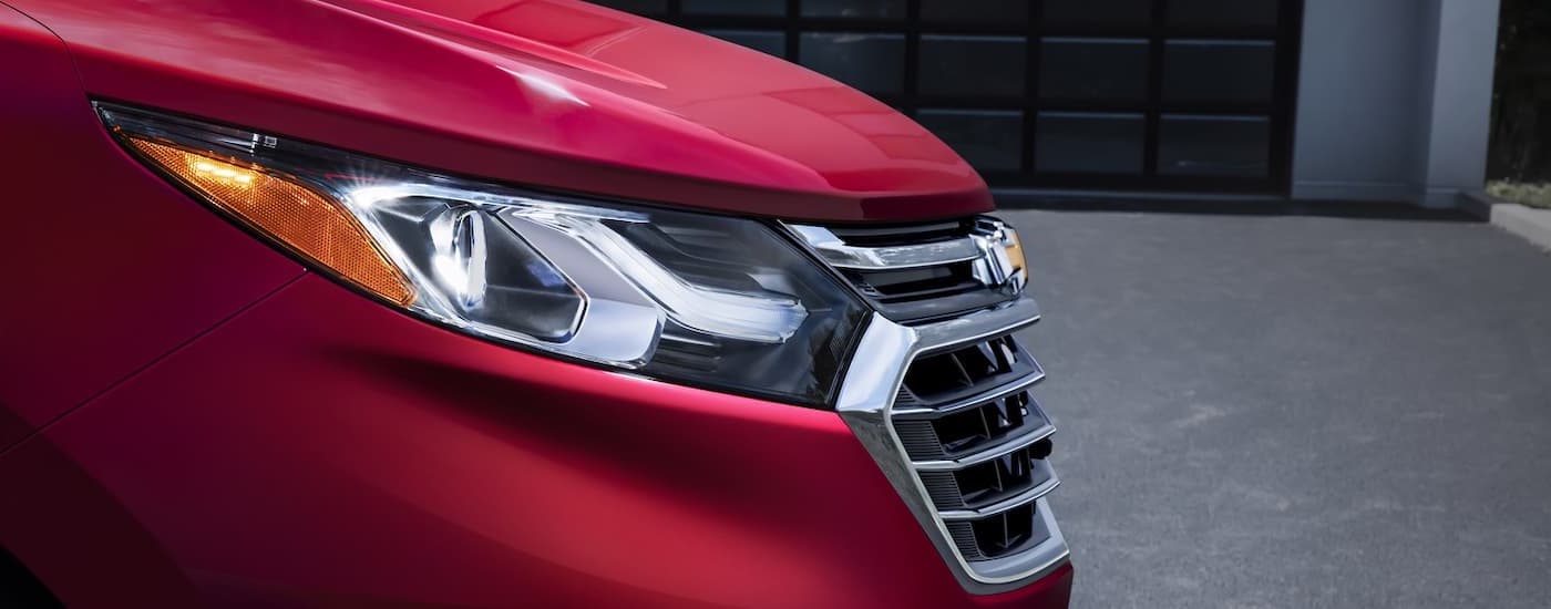 A close up shows the driver side headlight on a red 2018 Chevy Equinox.