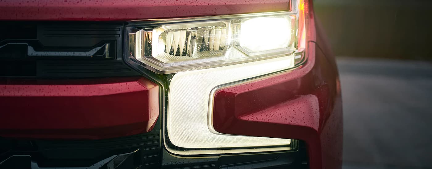 A close up shows the driver side headlight on a red 2022 Chevy Silverado 1500 after visiting a Chevy Silverado dealership.