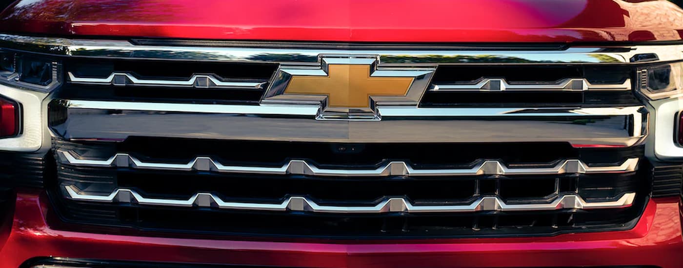 A close up of the grille on a red 2022 Chevy Silverado 1500 is shown at a Chevy Silverado dealership.
