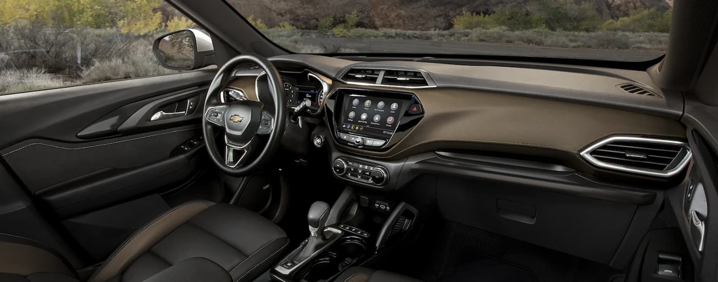 The black interior of a 2022 Chevy Trailblazer shows the steering wheel and infotainment screen.