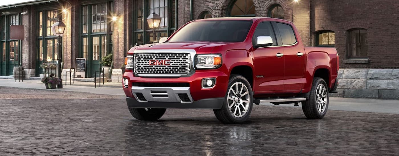 A red 2020 GMC Canyon is shown from the front parked in front of a building.