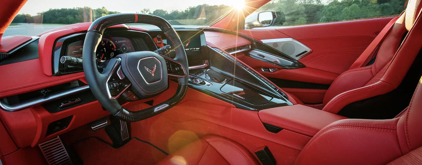The red interior of a 2023 Chevy Corvette Z06 shows the steering wheel and front seats.
