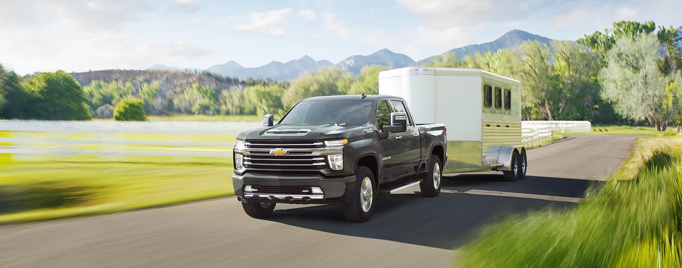 A black 2022 Chevy Silverado 3500 HD is shown towing a horse trailer after leaving a Miami, OK Chevy dealer.