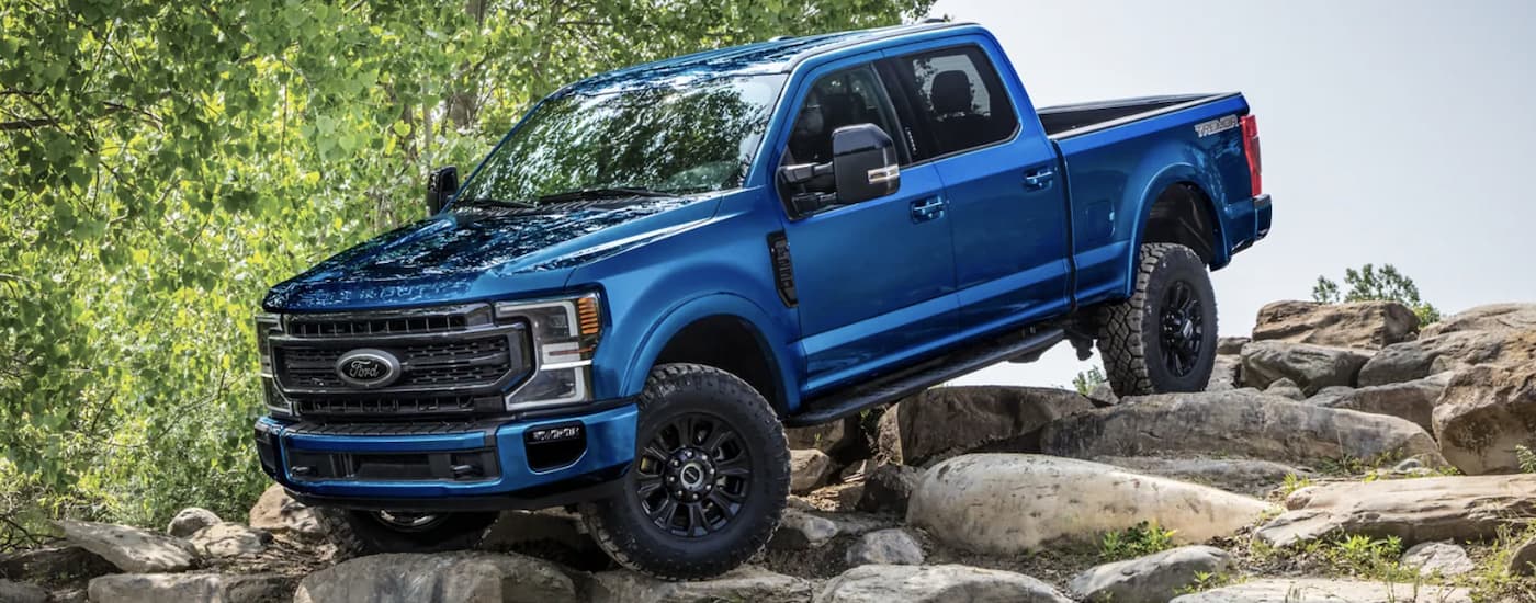 A blue 2022 Ford F-250 is shown off-roading in the mountains.