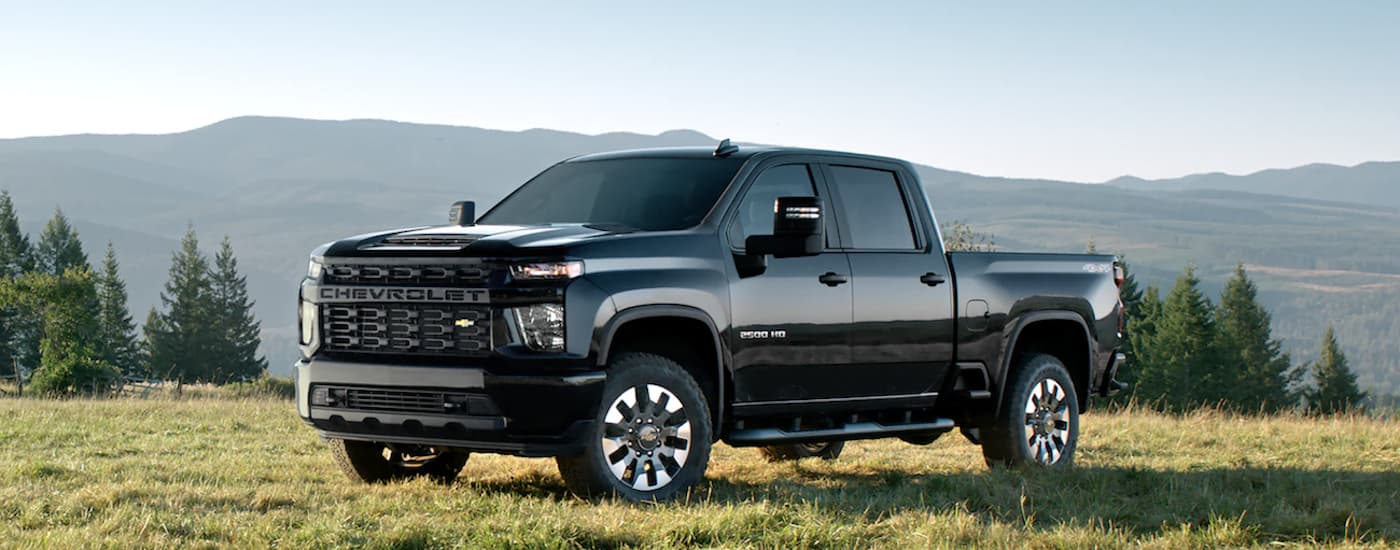 A black 2022 Chevy Silverado 2500 HD is shown from the side parked in a field.