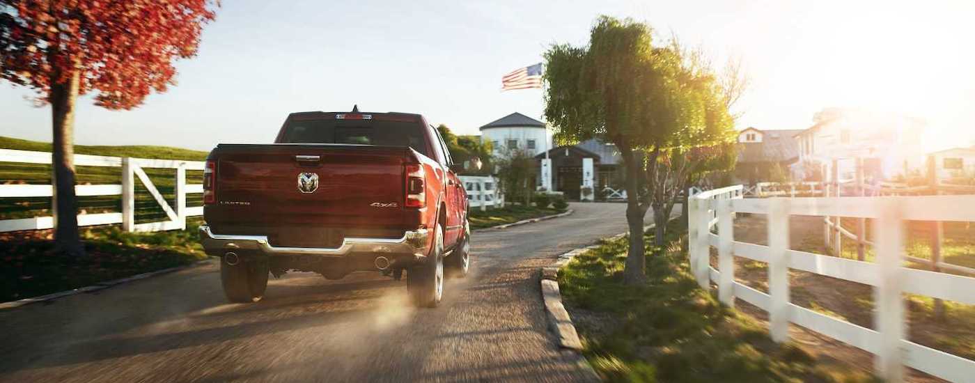 A red 2020 Ram 1500 Limited is shown driving on a dirt path past a white fence.