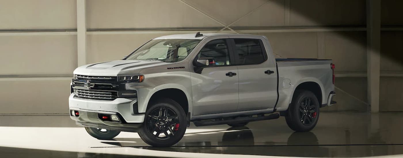 A silver 2021 Chevy Silverado 1500 is shown from the side parked in a gallery.