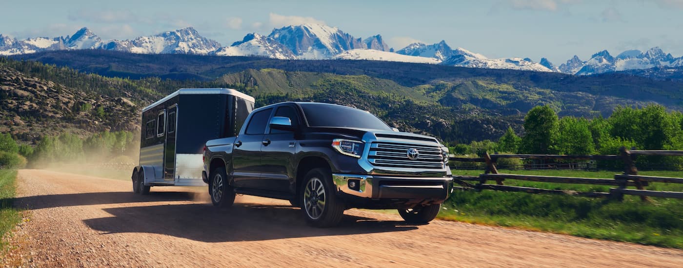 A black 2021 Toyota Tundra 1794 Edition CrewMax is shown towing a trailer on a dirt path.