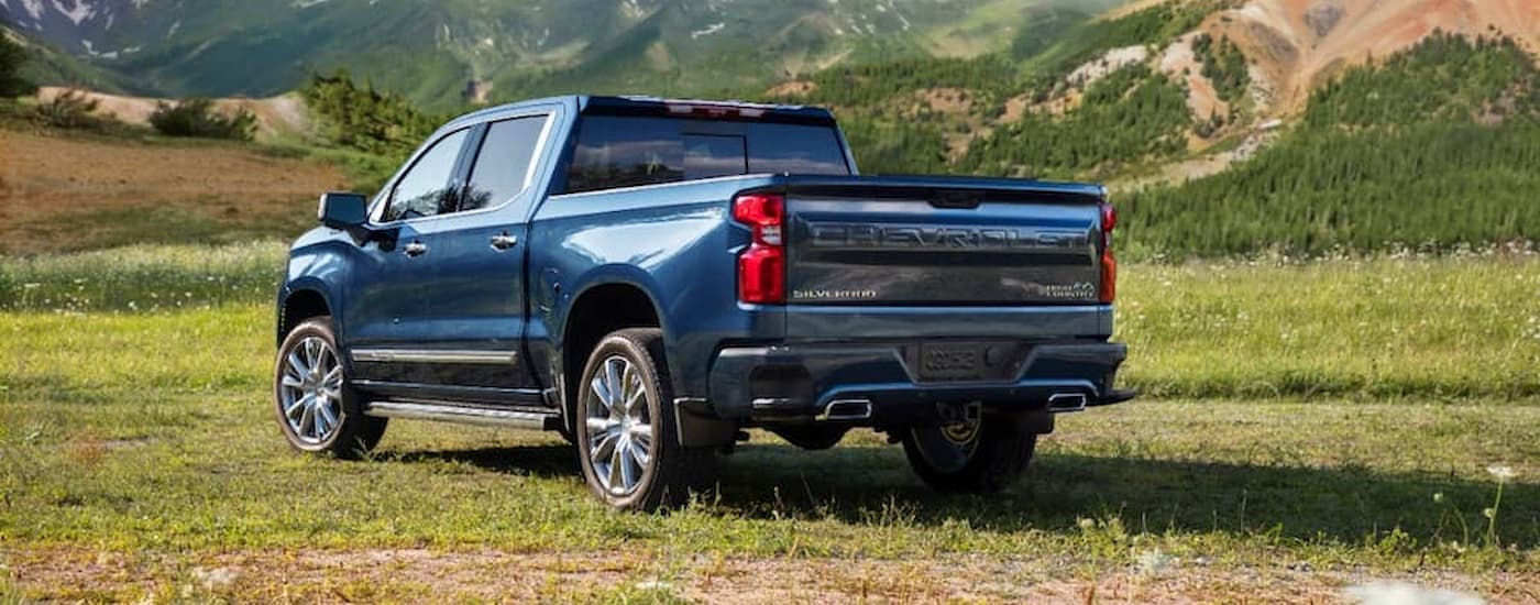 A blue 2022 Chevy Silverado High Country is shown from the rear in an open field.