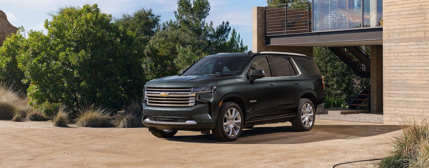 A green 2022 Chevy Tahoe High Country is shown parked in front of a driveway.