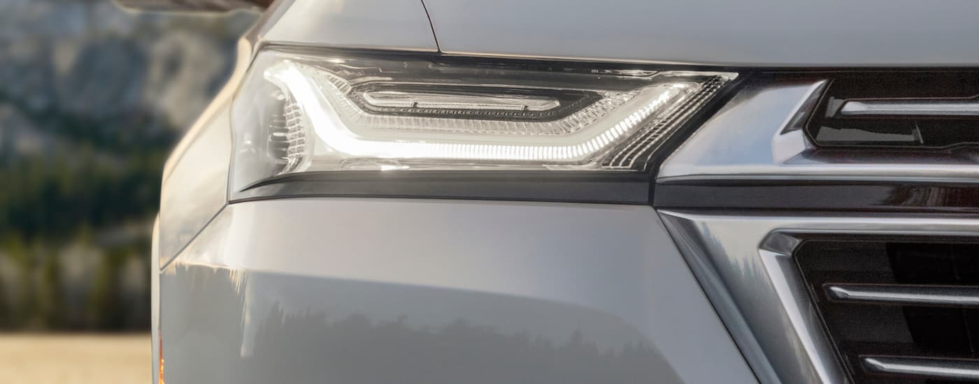 A close up shows the passenger side headlight on a white 2022 Chevy Traverse Premium.