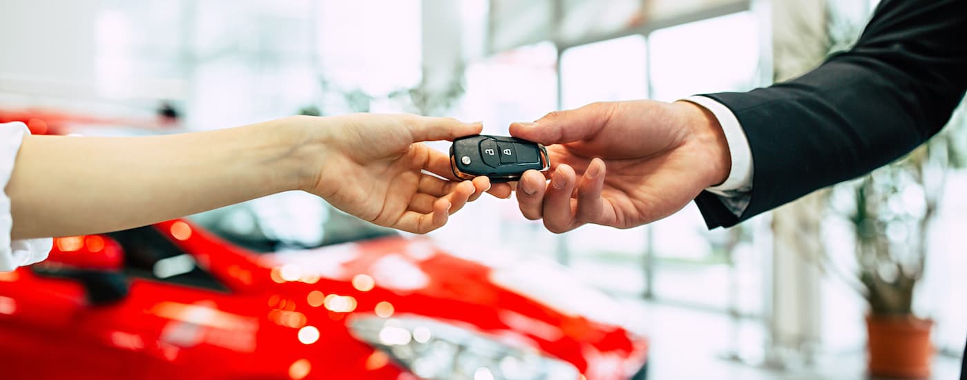 A car key is shown being passed at a car dealer.