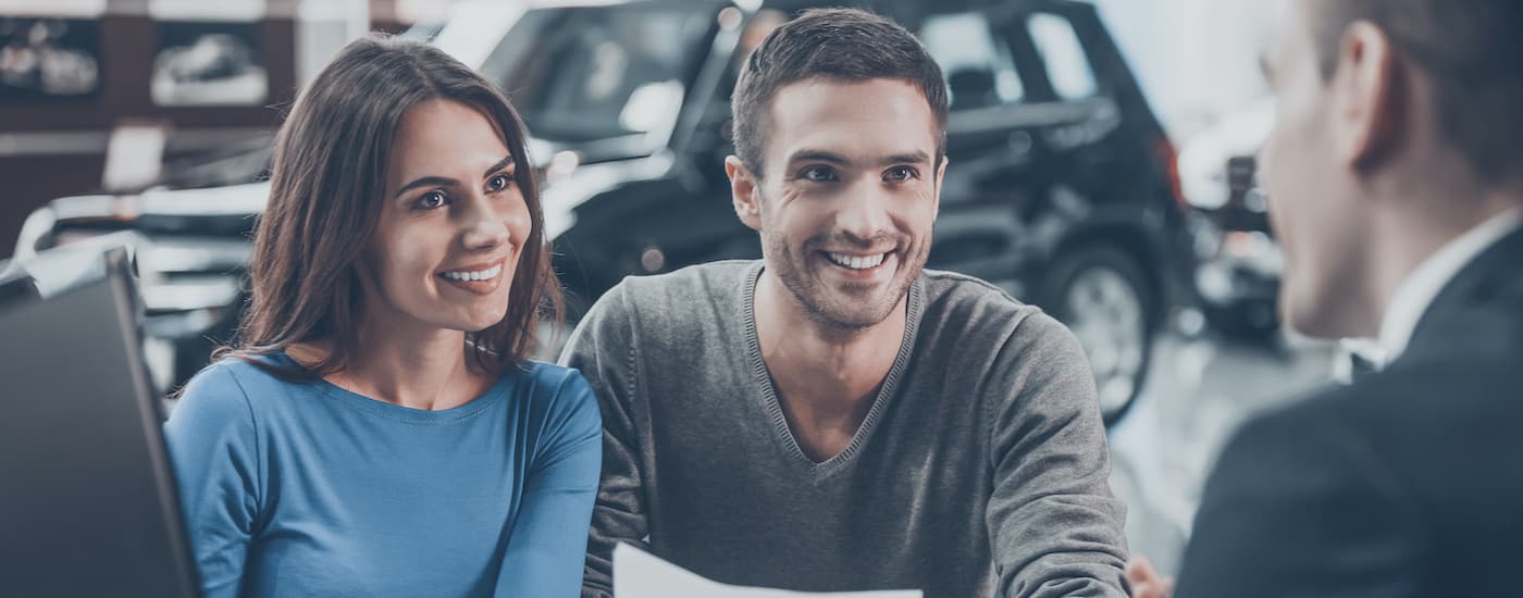 A couple is shown talking to a salesperson about trading in their car.