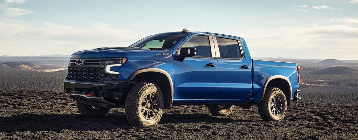 A blue 2022 Chevy Silverado 1500 ZR2 is shown off-roading in the mountains.