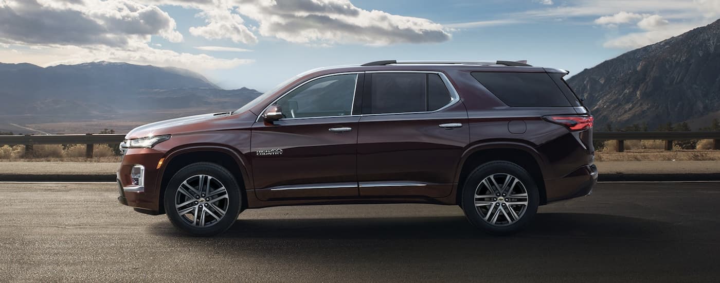 A maroon 2022 Chevy Traverse is shown from the side driving on a highway.