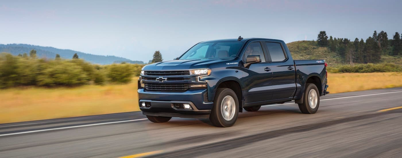A blue 2022 Chevy Silverado 1500 is shown from the side driving on a highway.