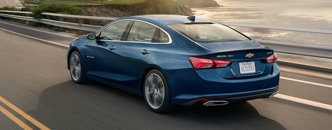 A blue 2022 Chevy Malibu is shown from the rear driving on an open road.