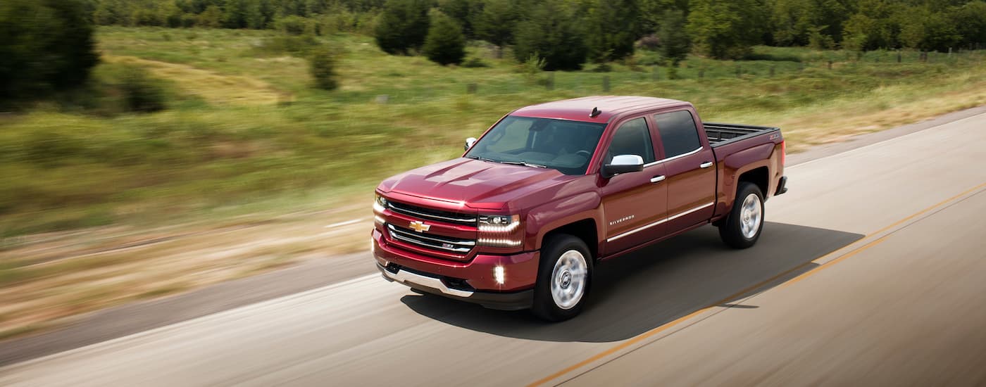A maroon 2017 Chevy Silverado 1500 LTZ Z71 is shown driving on an open road after leaving a used car dealer near you.