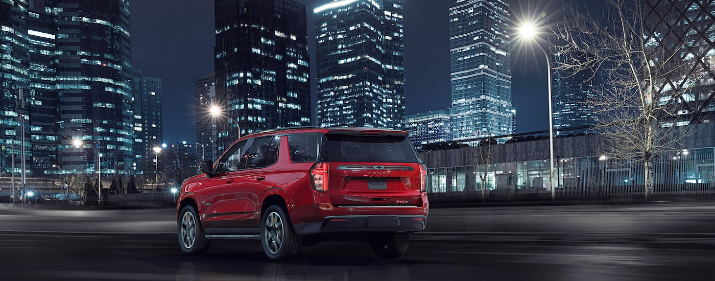 A red 2021 Chevy Tahoe RST is shown from behind parked on a city street at night.