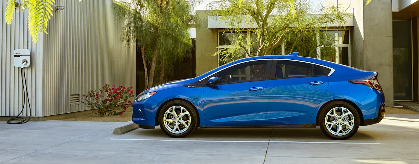 A blue 2016 Chevy Volt is shown from the side near a charger.