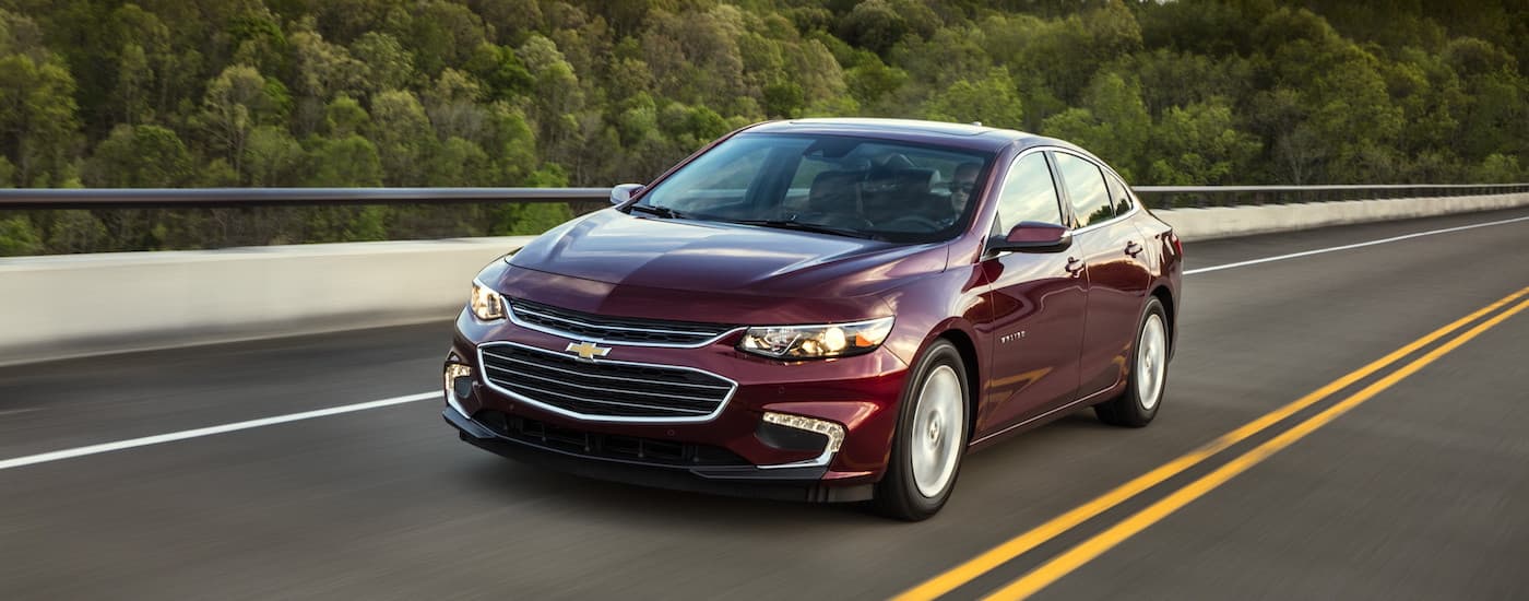A maroon 2018 Chevy Malibu Hybrid is shown driving on a highway.