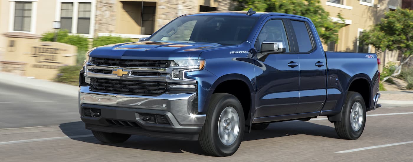 A blue 2019 Chevy Silverado 1500 is shown from the side driving through a city.
