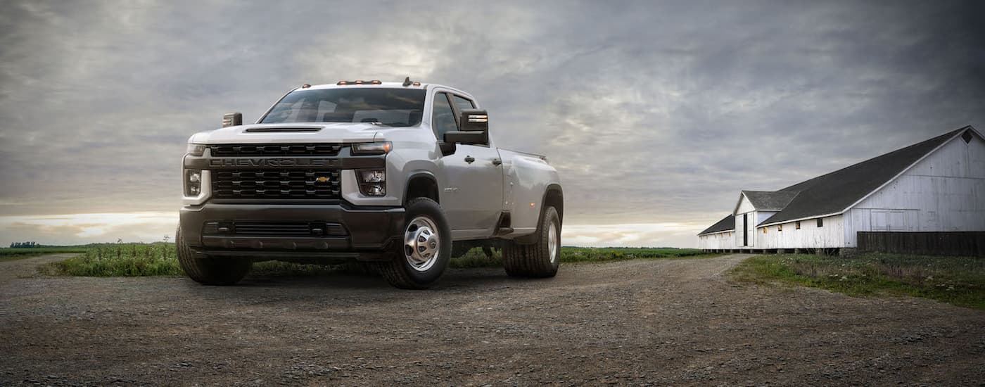 A white 2021 Chevy Silverado 3500HD is shown parked on a dirt road after viewing used diesel trucks.