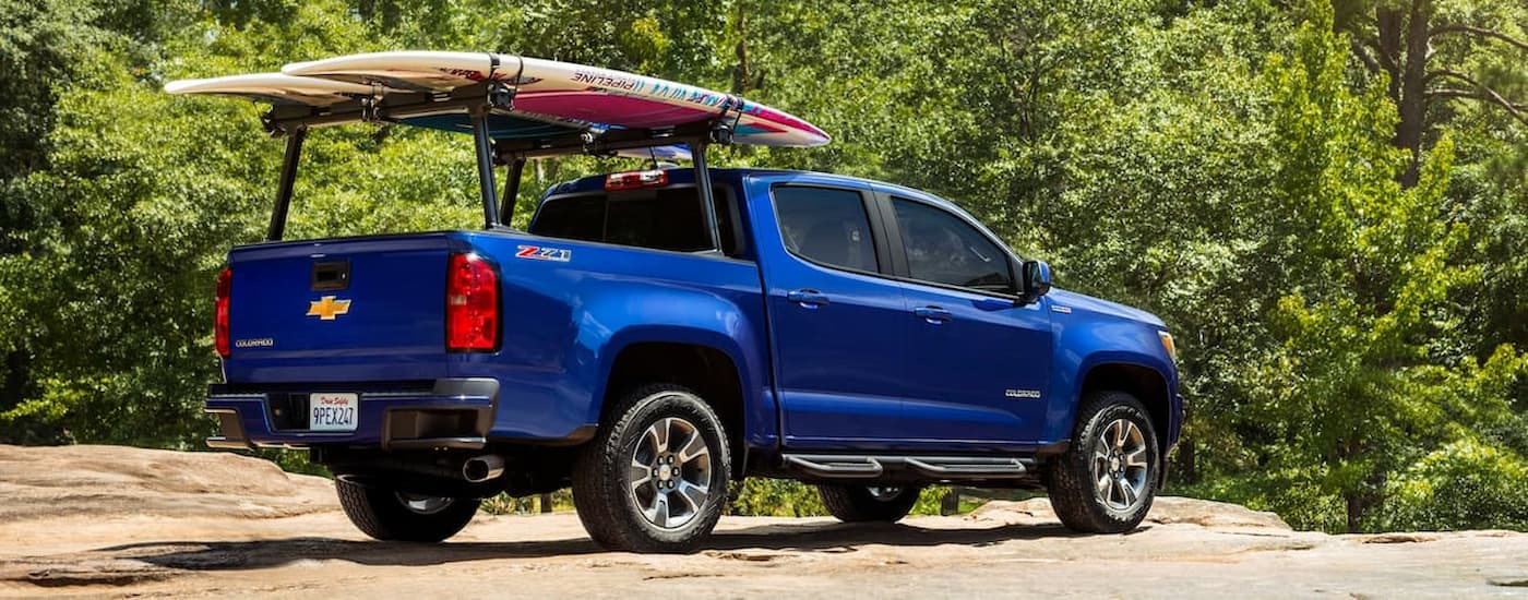 A blue 2019 Chevy Colorado is shown from the rear parked on a sandy area.