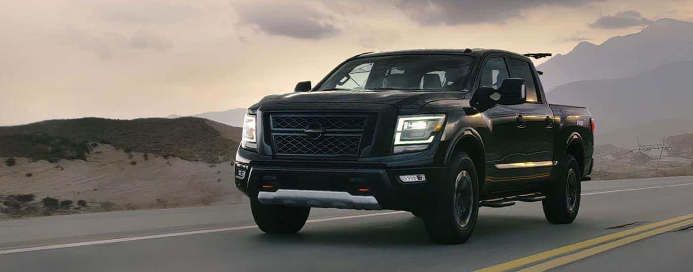 A black 2020 Nissan Titan is shown driving on an open highway.