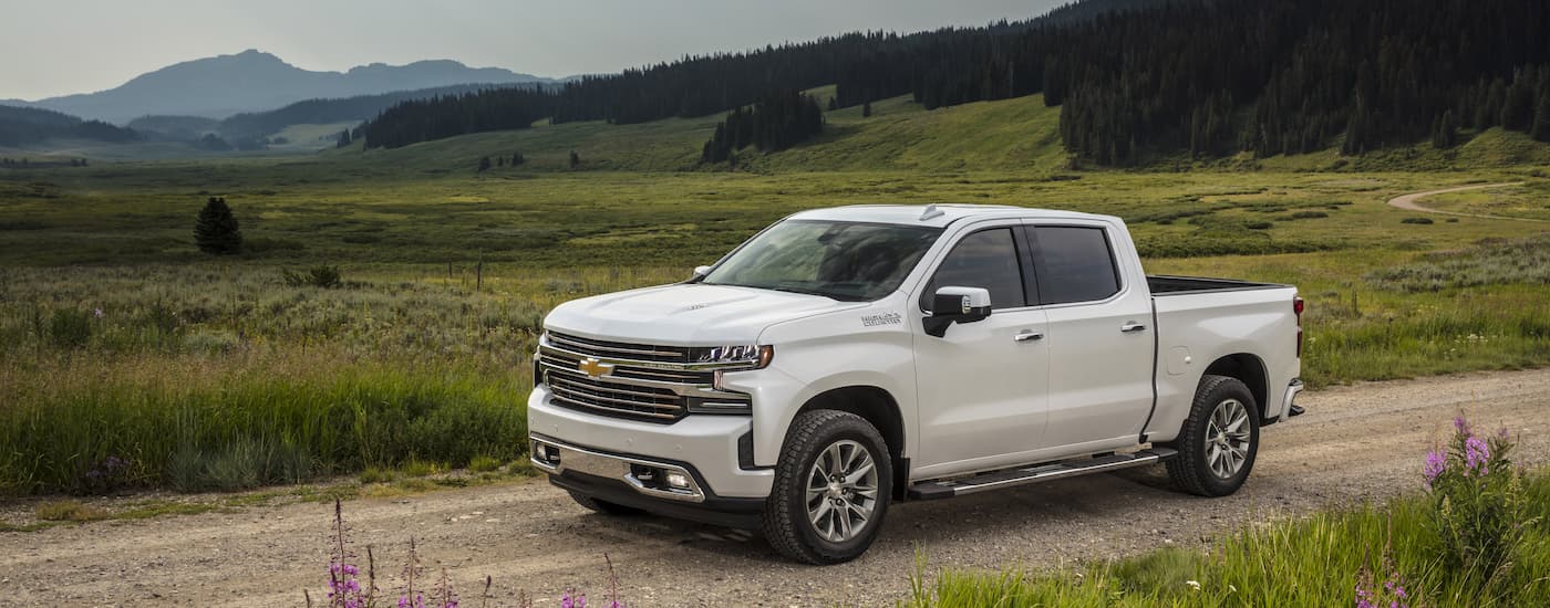 A white 2021 Chevy Silverado High Country is shown driving on a dirt road after leaving a used truck dealer near you.