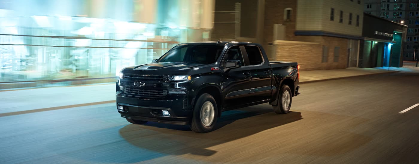 A black 2021 Chevy Silverado 1500 Z71 is shown driving on a city street at night.