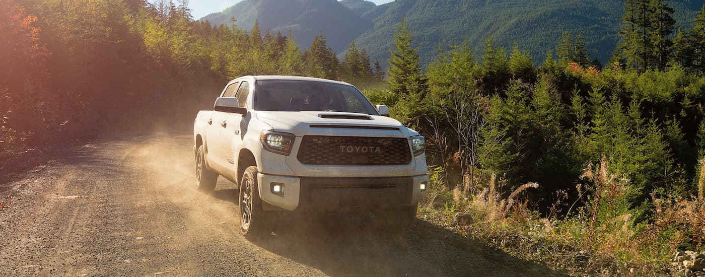 A white 2021 Toyota Tundra is shown from the front driving on a dirt road.