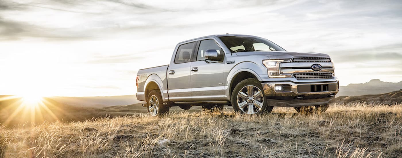 A silver 2018 Ford F-150 is shown at a dry grassy field after viewing used truck sales near you.