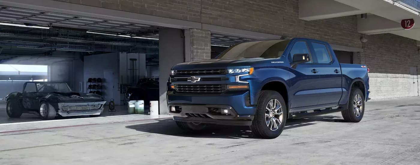 A popular vehicle for used truck sales near you, a dark blue 2020 Chevy Silverado 1500 RST, is shown parked in front of a garage.