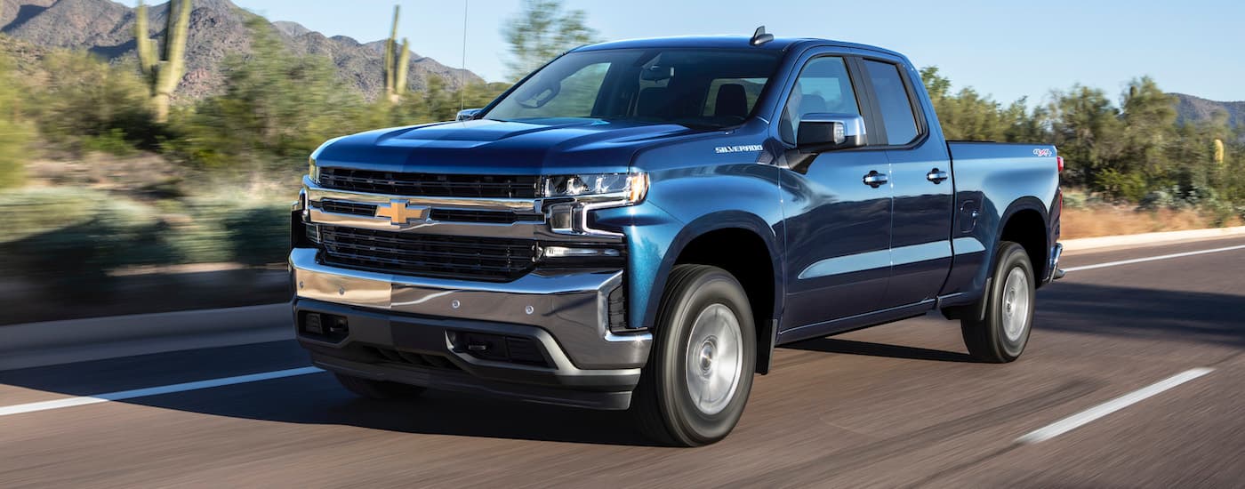 A blue 2019 Chevy Silverado 1500 is shown driving on an open road after viewing used truck for sales.
