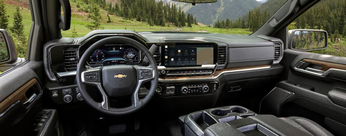 A view of the black interior of a 2022 Chevy Silverado 1500 LT is shown overlooking an open field.