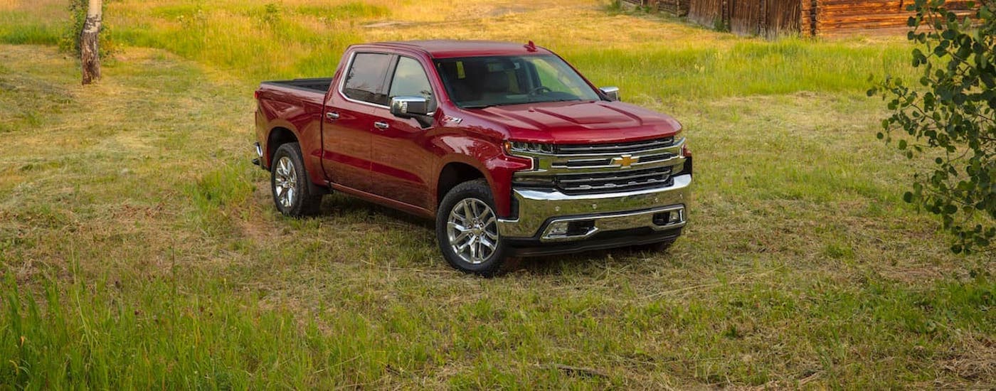 A red 2020 Chevy Silverado 1500 is shown from the front parked in a grass field.