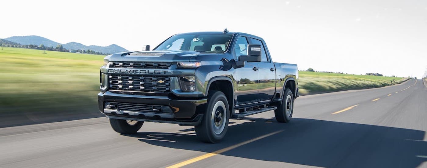 A black 2020 Chevy Silverado 2500 HD is shown from the front driving on a highway after searching 'used truck for sale.'