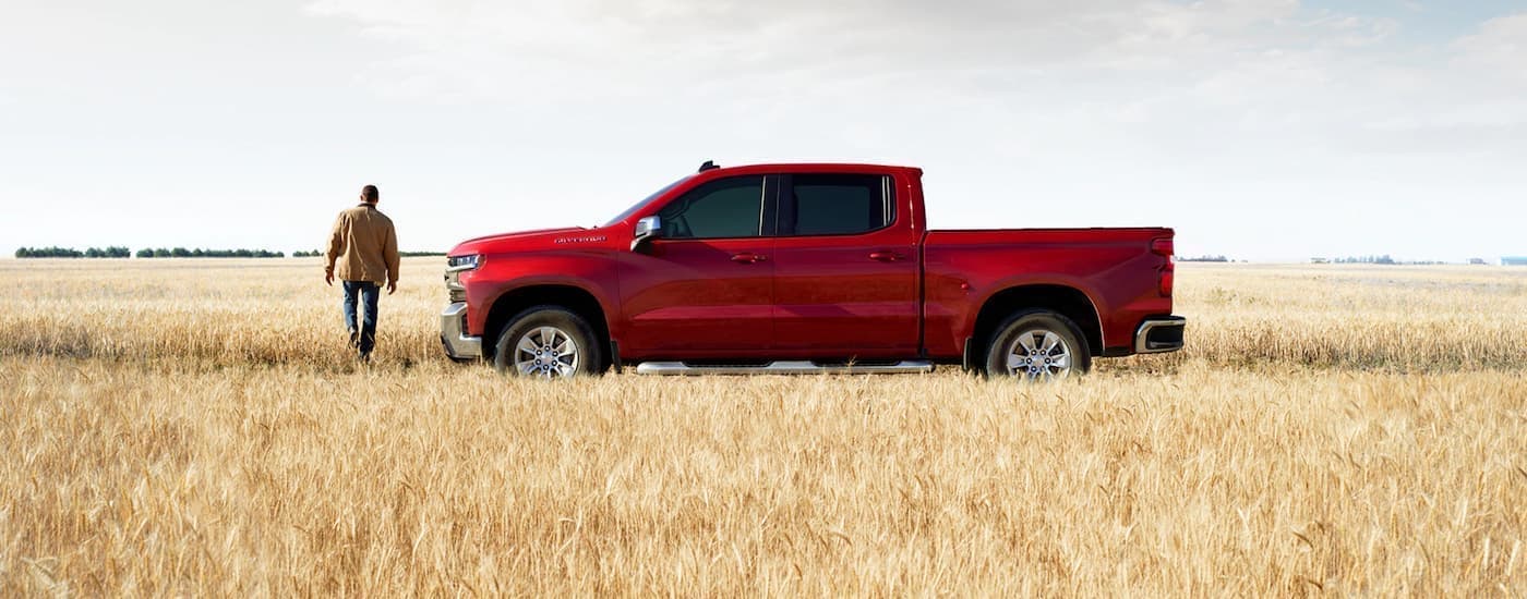 A red 2020 Chevy Silverado 1500 is shown from the side parked in a field after leaving a diesel truck dealership.