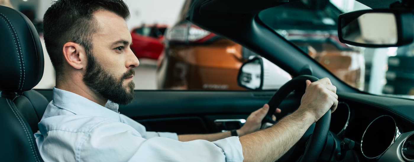A person is shown sitting in the drivers seat of a car at a dealership after deciding to sell their car.