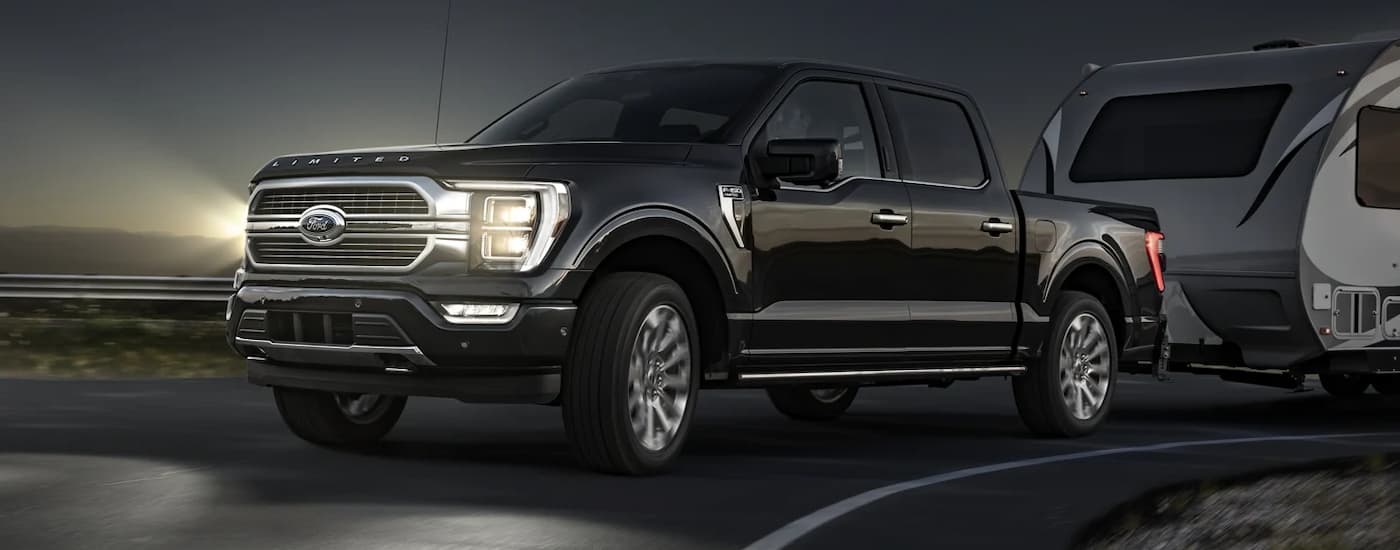 A black 2022 Ford F-150 is shown towing a trailer at night.