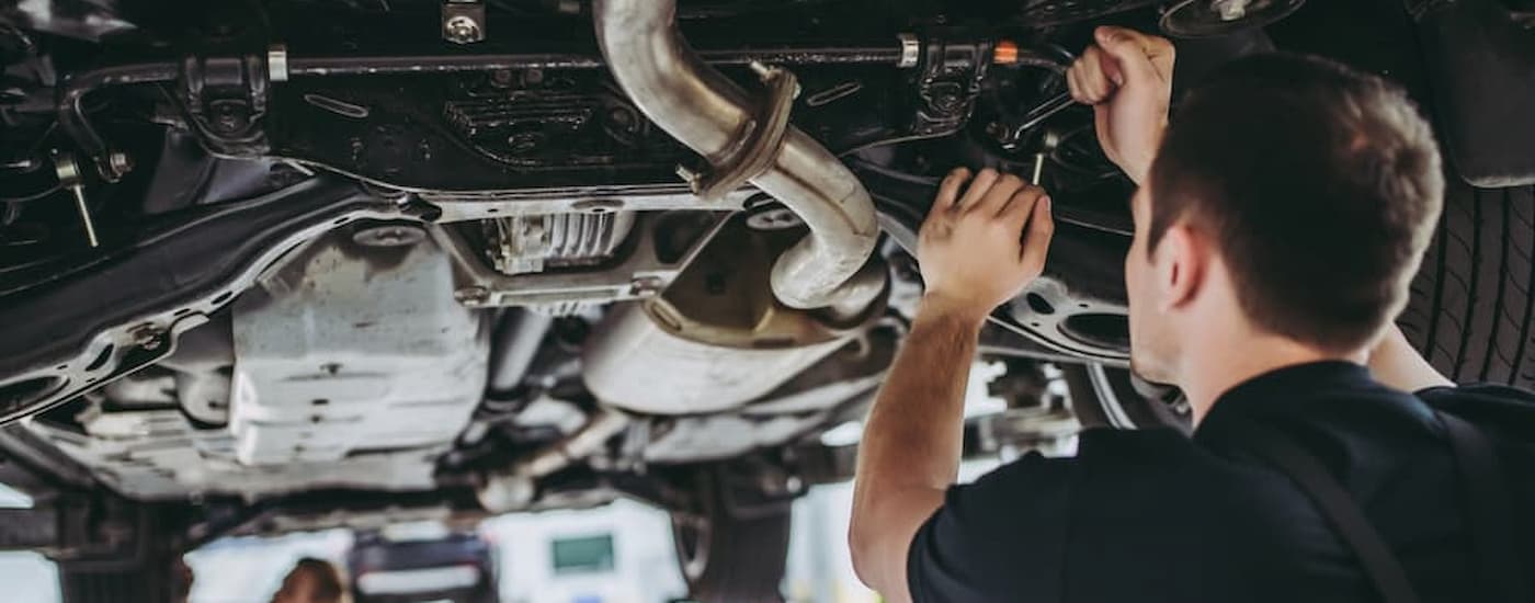 A mechanic is shown working underneath a vehicle at a repair shop.