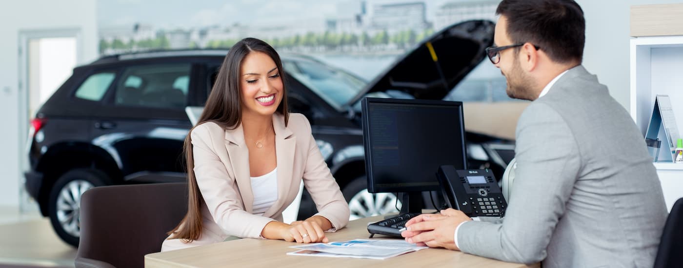 A person is shown talking to a sales person about selling their car.